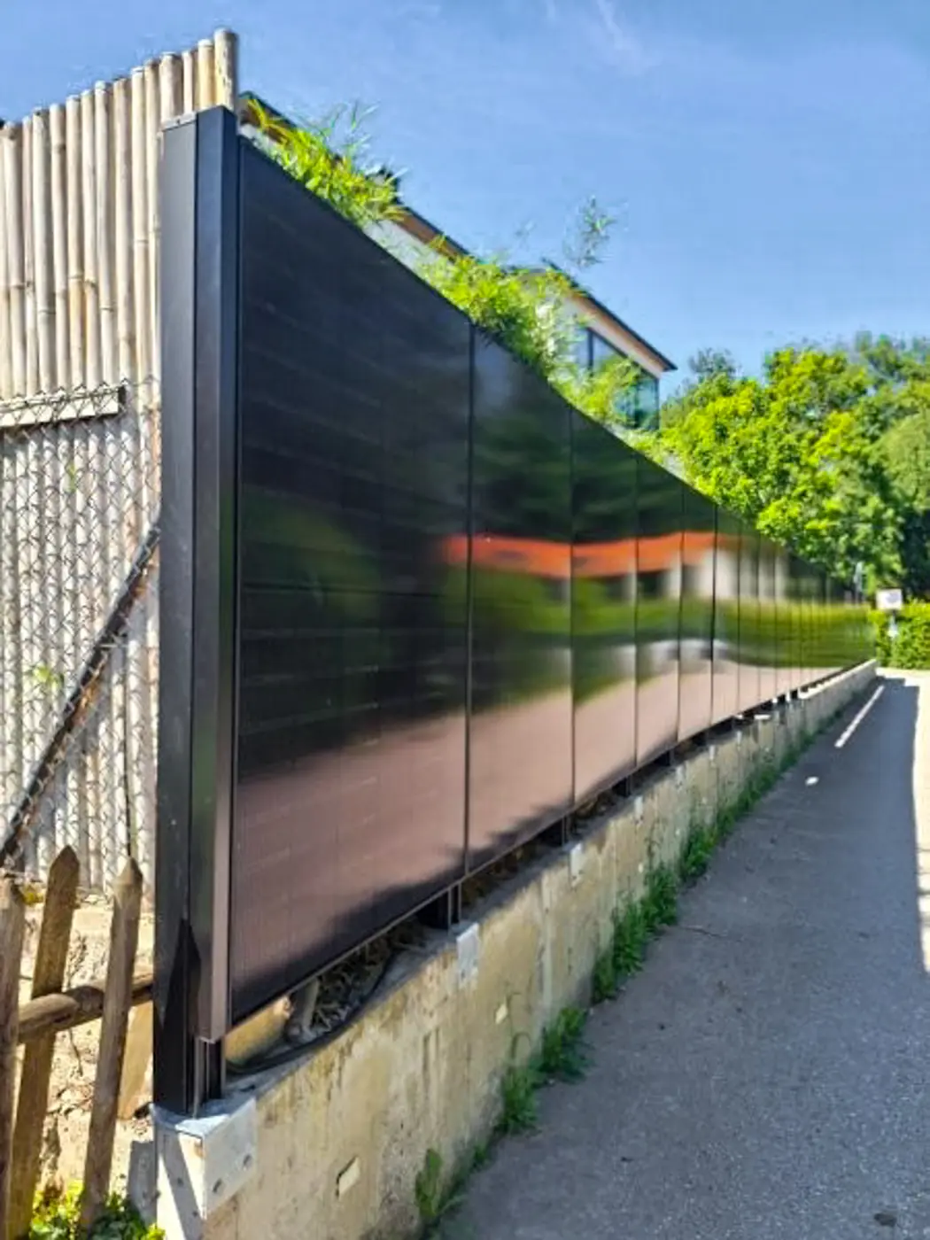 Solarzaun entlang eines schmalen Gehwegs