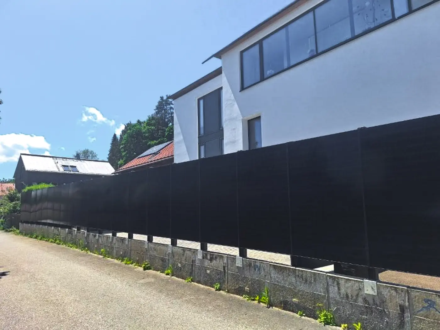 Solarzaun aus schwarzen Glas-Glas-Modulen entlang einer Straße