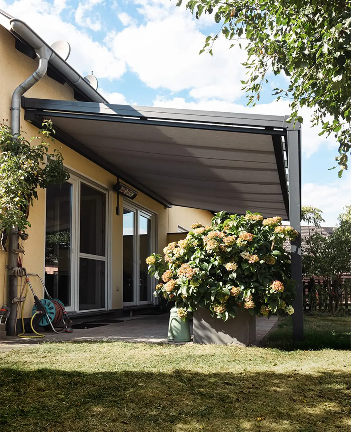 Terrassendach mit Unterdachmarkise vor einem gelben Haus
